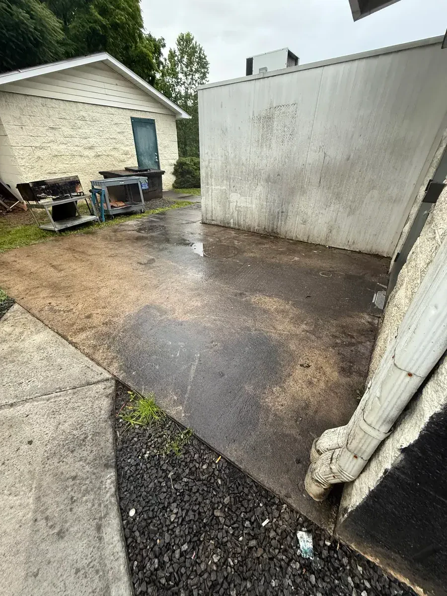 Grease-stained concrete pad before pressure washing